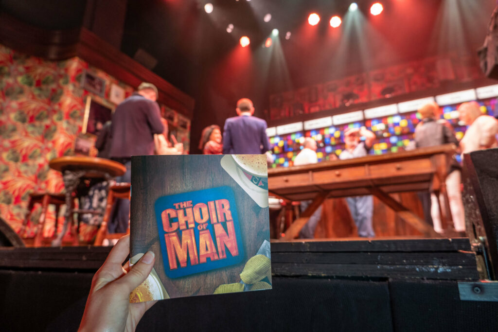 The Choir of Man programme in front of the The Arts Theatre stage, London