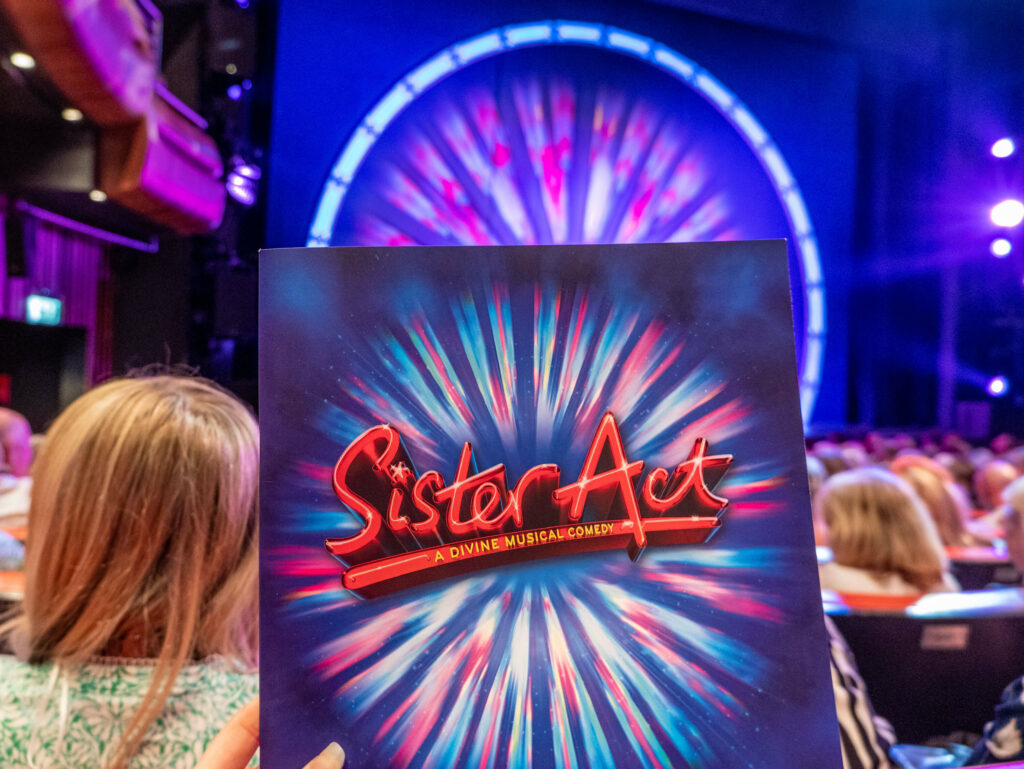Sister Act programme in front of The Marlowe Theatre stage in Canterbury, Kent