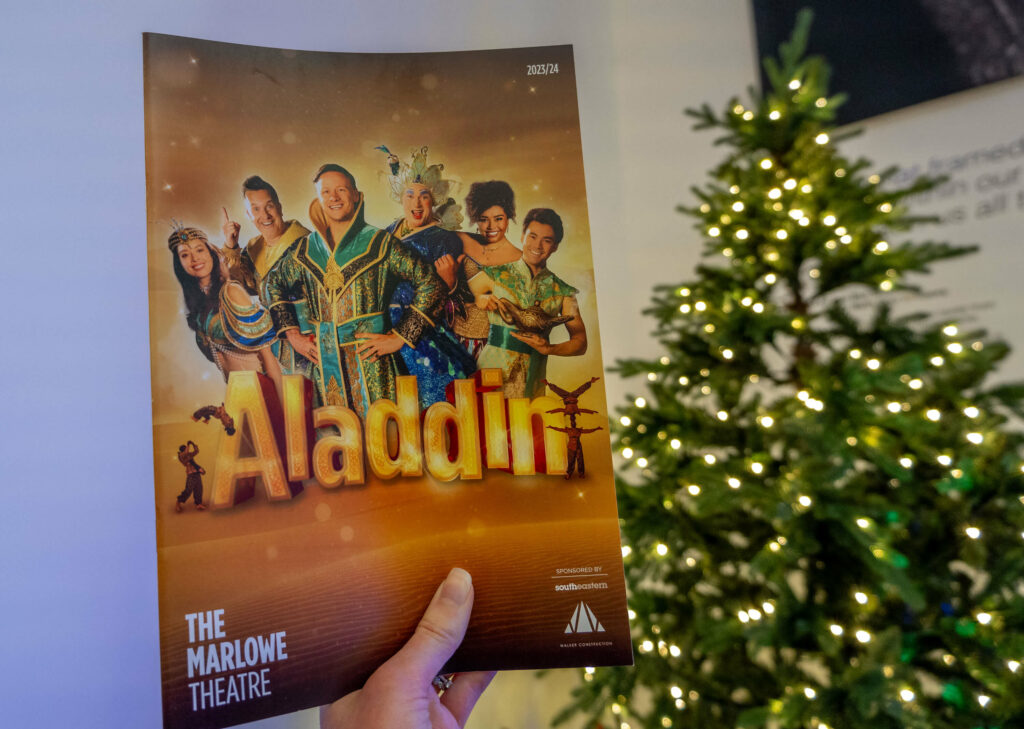 Aladdin programme in front of The Marlowe Theatre Christmas tree in Canterbury, Kent
