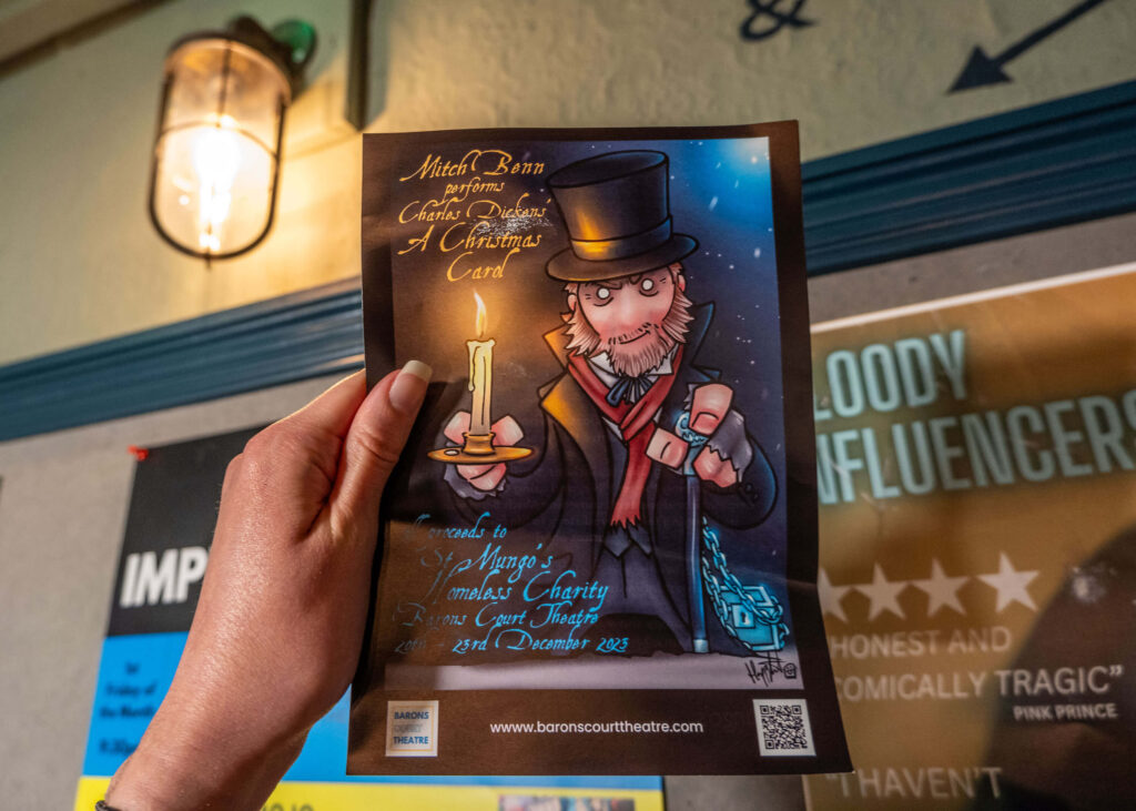 A Christmas Carol leaflet in front of a lantern-inspired light at Barons Court Theatre, London