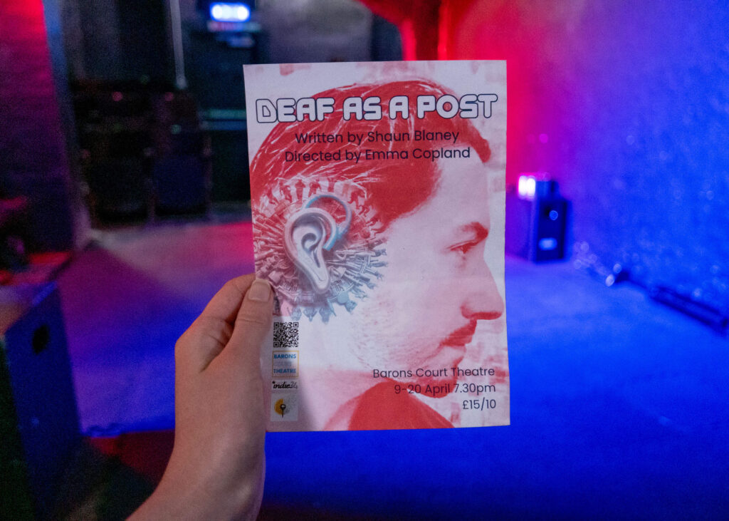 Deaf as a Post leaflet in front of the Barons Court Theatre stage in London