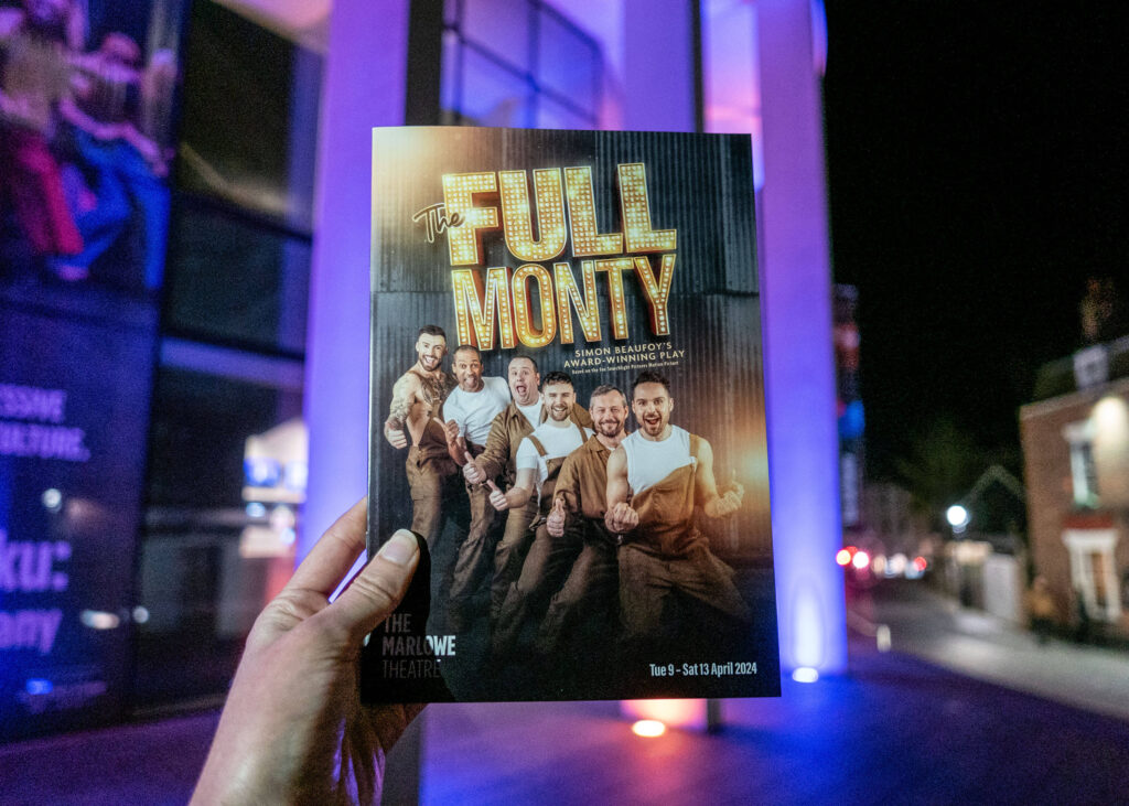 The Full Monty programme outside The Marlowe Theatre at night, Canterbury