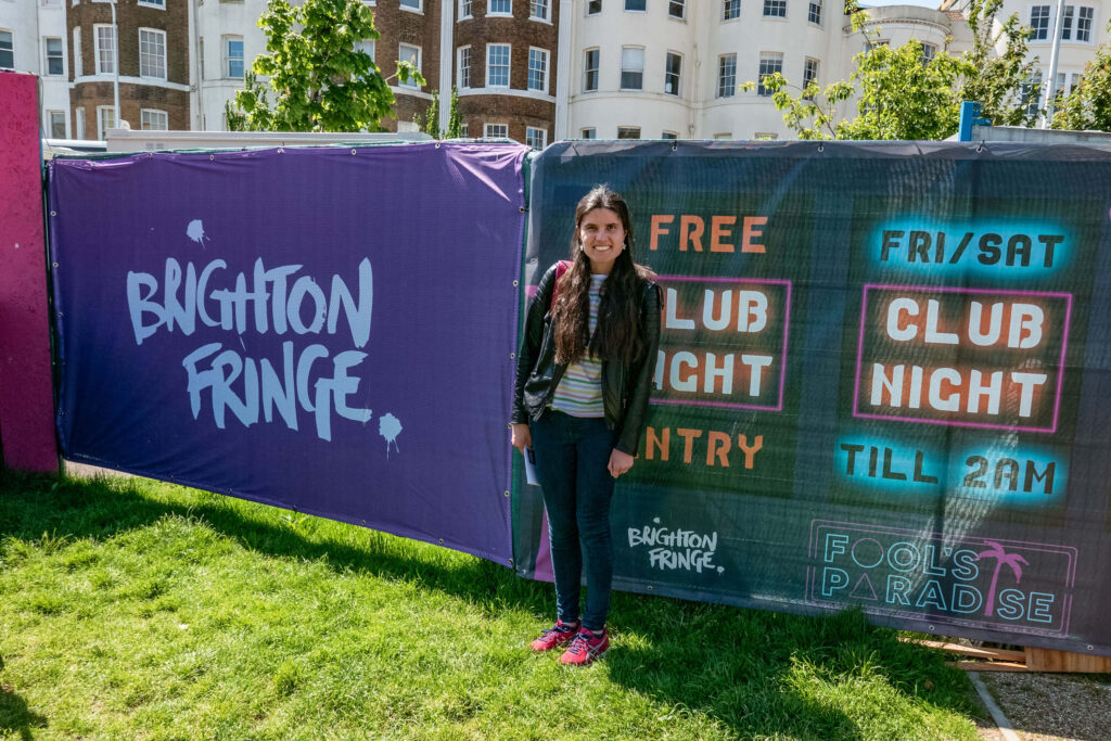 Kat Masterson next to Brighton Fringe banners at Fool's Paradise